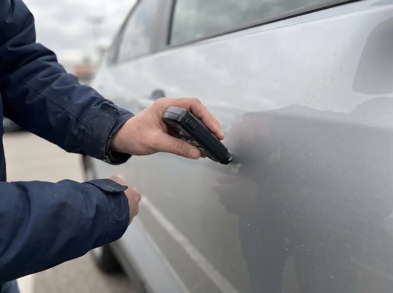 Messung der Lackschichtdicke an der Tür eines silbernen Autos
